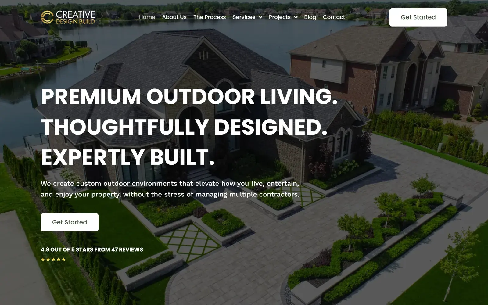 Creative Design Build homepage on desktop, with the headline Premium Outdoor Living. Thoughtfully Designed. Expertly Built. over an aerial photo of a lakeside home with landscaped paving, and white Get Started buttons